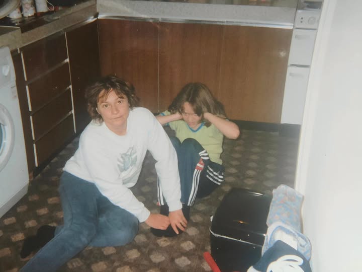 A childhood photo of joey and her mum sitting on a kitchen floor, one holding the other's feet down during sit-ups. 